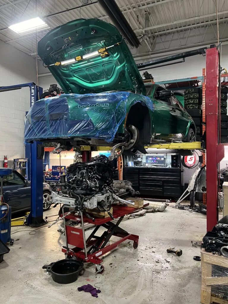 Green BMW on the hoist with its engine out